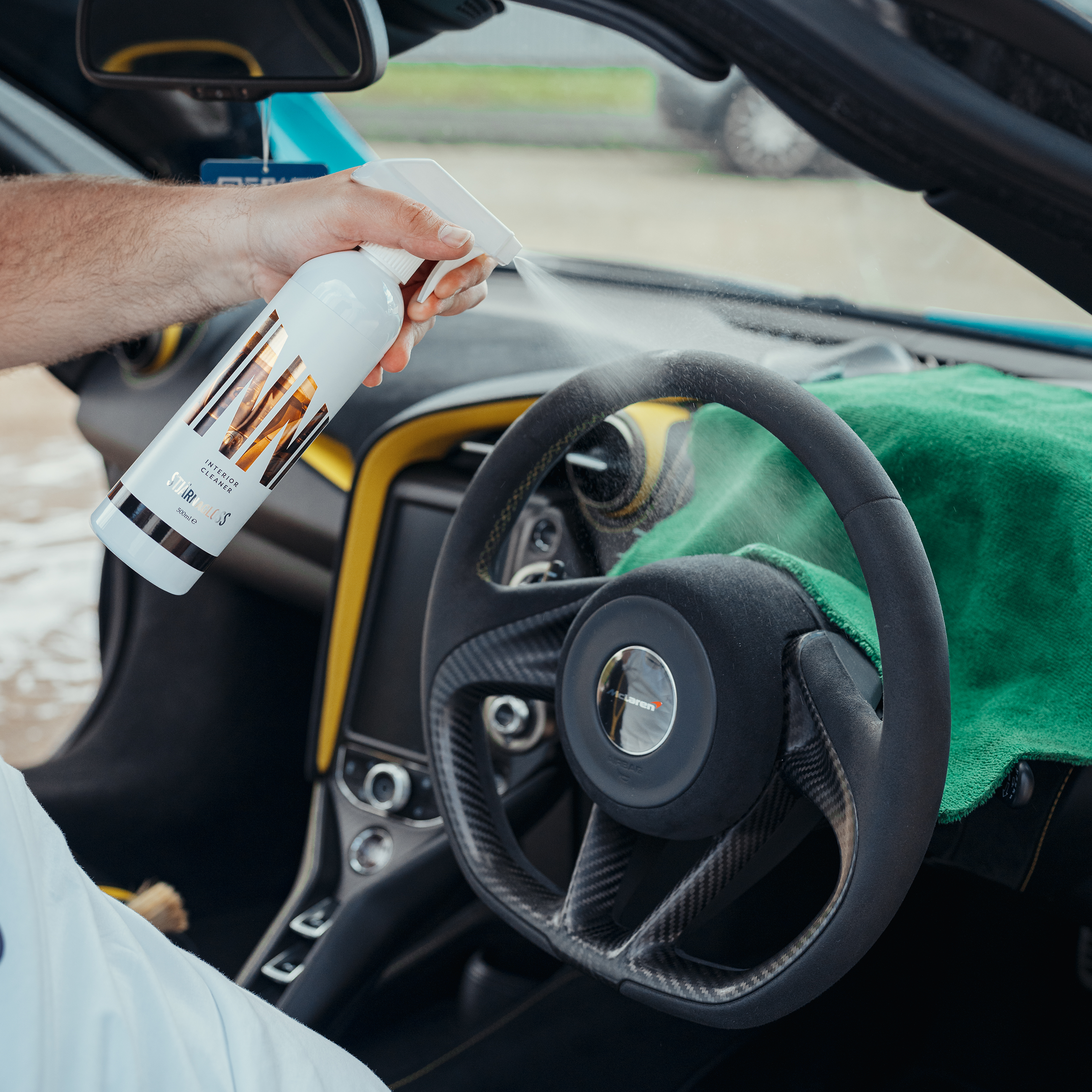 spraying Inni - All-Surface Interior Car Cleaner on car wheel